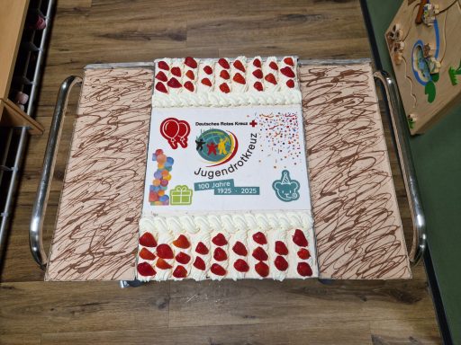 Bunte Sahnetorte mit Erdbeeren und dekorativen Mustern auf einem Tablett.